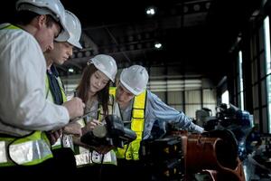 team engineers inspecting on machine with smart tablet. Worker works at heavy machine robot arm. The welding machine with a remote system in an industrial factory. Artificial intelligence concept. photo