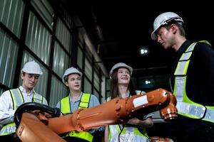 team engineers inspecting on machine with smart tablet. Worker works at heavy machine robot arm. The welding machine with a remote system in an industrial factory. Artificial intelligence concept. photo