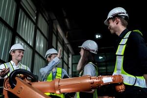 team engineers inspecting on machine with smart tablet. Worker works at heavy machine robot arm. The welding machine with a remote system in an industrial factory. Artificial intelligence concept. photo