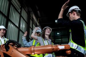 team engineers inspecting on machine with smart tablet. Worker works at heavy machine robot arm. The welding machine with a remote system in an industrial factory. Artificial intelligence concept. photo