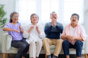 Happiness of the group females and male elderly sitting on the sofa. Senior people are talking and enjoy together at the living room. Joyful carefree retired senior friends enjoying relaxation. photo
