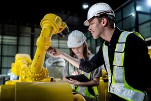 team engineers inspecting on machine with smart tablet. Worker works at heavy machine robot arm. The welding machine with a remote system in an industrial factory. Artificial intelligence concept. photo