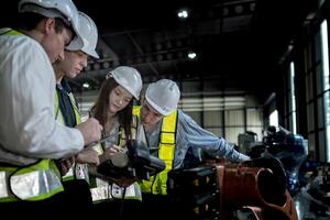 team engineers inspecting on machine with smart tablet. Worker works at heavy machine robot arm. The welding machine with a remote system in an industrial factory. Artificial intelligence concept. photo