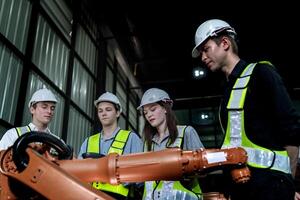 team engineers inspecting on machine with smart tablet. Worker works at heavy machine robot arm. The welding machine with a remote system in an industrial factory. Artificial intelligence concept. photo