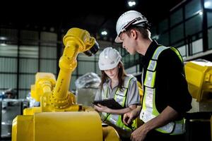 team engineers inspecting on machine with smart tablet. Worker works at heavy machine robot arm. The welding machine with a remote system in an industrial factory. Artificial intelligence concept. photo