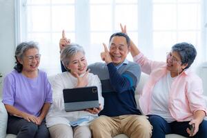 Happiness of the group females and male elderly talking with Call from smart tablet. Senior people are talking and enjoy together at the living room. Joyful retired friends enjoying relaxation. photo