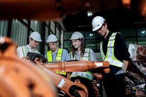 team engineers inspecting on machine with smart tablet. Worker works at heavy machine robot arm. The welding machine with a remote system in an industrial factory. Artificial intelligence concept. photo