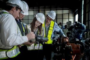 team engineers inspecting on machine with smart tablet. Worker works at heavy machine robot arm. The welding machine with a remote system in an industrial factory. Artificial intelligence concept. photo