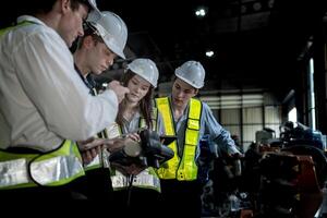 team engineers inspecting on machine with smart tablet. Worker works at heavy machine robot arm. The welding machine with a remote system in an industrial factory. Artificial intelligence concept. photo