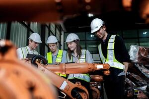 team engineers inspecting on machine with smart tablet. Worker works at heavy machine robot arm. The welding machine with a remote system in an industrial factory. Artificial intelligence concept. photo