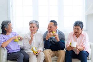 Happiness of the group females and male elderly sitting on the sofa. Senior people are talking and enjoy together at the living room. Joyful carefree retired senior friends enjoying relaxation. photo