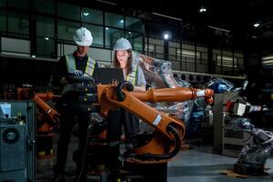 team engineers inspecting on machine with smart tablet. Worker works at heavy machine robot arm. The welding machine with a remote system in an industrial factory. Artificial intelligence concept. photo
