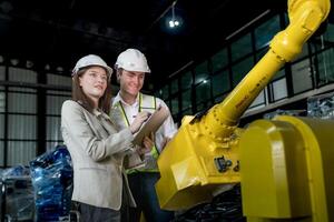 team engineers inspecting on machine with smart tablet. Worker works at heavy machine robot arm. The welding machine with a remote system in an industrial factory. Artificial intelligence concept. photo