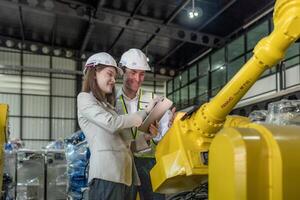 team engineers inspecting on machine with smart tablet. Worker works at heavy machine robot arm. The welding machine with a remote system in an industrial factory. Artificial intelligence concept. photo
