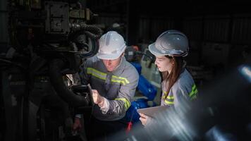 team engineers inspecting on machine with smart tablet. Worker works at heavy machine robot arm. The welding machine with a remote system in an industrial factory. Artificial intelligence concept. photo