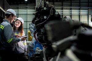 team engineers inspecting on machine with smart tablet. Worker works at heavy machine robot arm. The welding machine with a remote system in an industrial factory. Artificial intelligence concept. photo