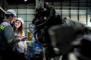 team engineers inspecting on machine with smart tablet. Worker works at heavy machine robot arm. The welding machine with a remote system in an industrial factory. Artificial intelligence concept. photo