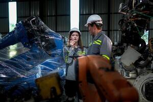 team engineers inspecting on machine with smart tablet. Worker works at heavy machine robot arm. The welding machine with a remote system in an industrial factory. Artificial intelligence concept. photo