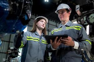 team engineers inspecting on machine with smart tablet. Worker works at heavy machine robot arm. The welding machine with a remote system in an industrial factory. Artificial intelligence concept. photo