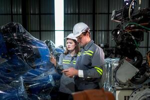 team engineers inspecting on machine with smart tablet. Worker works at heavy machine robot arm. The welding machine with a remote system in an industrial factory. Artificial intelligence concept. photo