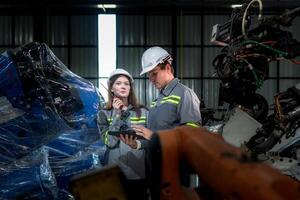 team engineers inspecting on machine with smart tablet. Worker works at heavy machine robot arm. The welding machine with a remote system in an industrial factory. Artificial intelligence concept. photo