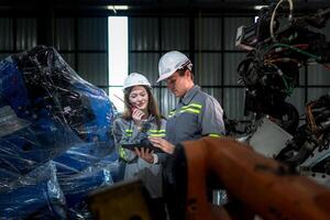 team engineers inspecting on machine with smart tablet. Worker works at heavy machine robot arm. The welding machine with a remote system in an industrial factory. Artificial intelligence concept. photo