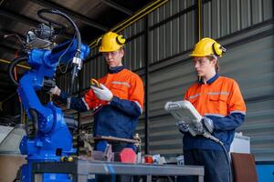 group of male engineer workers maintenance automatic robotic arm machine in a dark room factory. worker checking and repairing automatic robot hand machine. Worker wearing safety glasses and helmet. photo