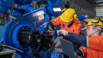 group of male engineer workers maintenance automatic robotic arm machine in a dark room factory. worker checking and repairing automatic robot hand machine. Worker wearing safety glasses and helmet. photo