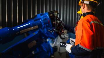 group of male engineer workers maintenance automatic robotic arm machine in a dark room factory. worker checking and repairing automatic robot hand machine. Worker wearing safety glasses and helmet. photo