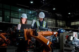 team engineers inspecting on machine with smart tablet. Worker works at heavy machine robot arm. The welding machine with a remote system in an industrial factory. Artificial intelligence concept. photo