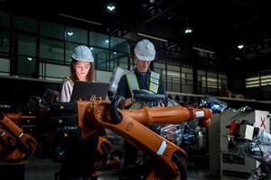 team engineers inspecting on machine with smart tablet. Worker works at heavy machine robot arm. The welding machine with a remote system in an industrial factory. Artificial intelligence concept. photo