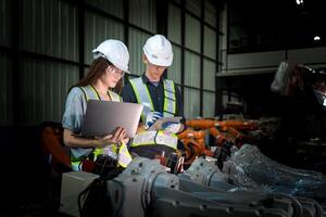 Sales manager and factory owner in suits negotiating selling robots used in the factory. Business engineers meeting and checking new machine robot. Workers walking at warehouse welding machine. photo