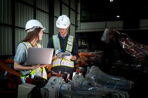 team engineers inspecting on machine with smart tablet. Worker works at heavy machine robot arm. The welding machine with a remote system in an industrial factory. Artificial intelligence concept. photo
