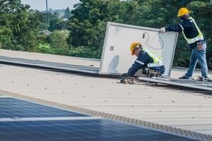 Worker Technicians are working to construct solar panels system on roof. Installing solar photovoltaic panel system. Men technicians carrying photovoltaic solar modules on roof. photo