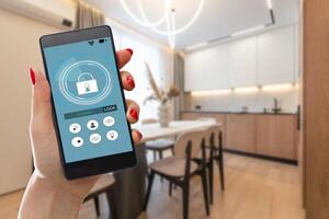 Young woman holding smart phone with launched security application at home. Concept of controlling and managing home security from a mobile device photo