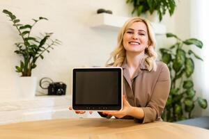 Woman displaying her tablet computer with the blank black screen turned to face the camera for your text or advertisement photo