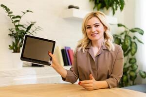 Woman displaying her tablet computer with the blank black screen turned to face the camera for your text or advertisement photo