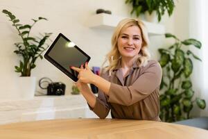 Woman displaying her tablet computer with the blank black screen turned to face the camera for your text or advertisement photo