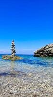 A tower of pebbles and stones at the beach, on a rock in the sea. A good analogy for balance and calmness. A deep blue palette is used. photo