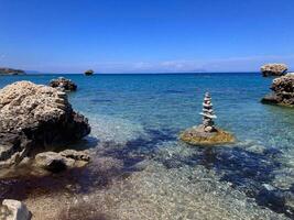Two tall towers of pebbles on a rock at the beach. A good analogy for balance, calmness and fortitude. A deep blue palette is used for the sea and sky. photo