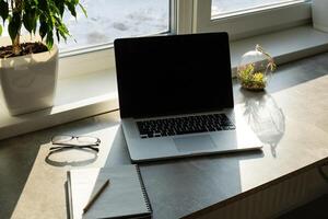Workplace with notebook laptop Comfortable work table in office with windows and city view photo