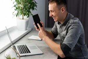 Excited worker sitting at desk in coworking space use computer reading message looking at device screen received great unbelievable opportunity or reward. Motivated employee celebrating job promotion photo