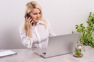 Portrait of a smiling young woman using laptop and smartphone photo