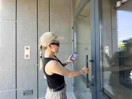 Woman locking smartlock on the entrance door using a smart phone. Concept of using smart electronic locks with keyless access. photo