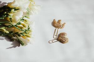 A decorative paper clip with a crown and a heart on a table with a bouquet of flowers. photo