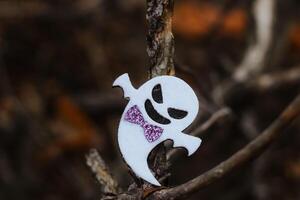 Toy ghost made of felt in the forest, Halloween decor photo