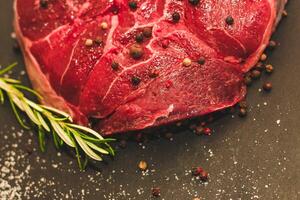 Fresh piece of meat large beef steak on the bone ossobuco with pepper on a black background. photo