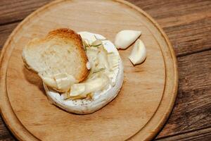 White baguette with olive oil and baked Camembert cheese on the table photo