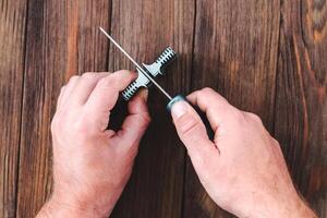 hands sharpening a knife on a wooden background photo