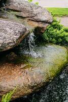 Artificial waterfall of stones and flowers in a landscaped green garden photo